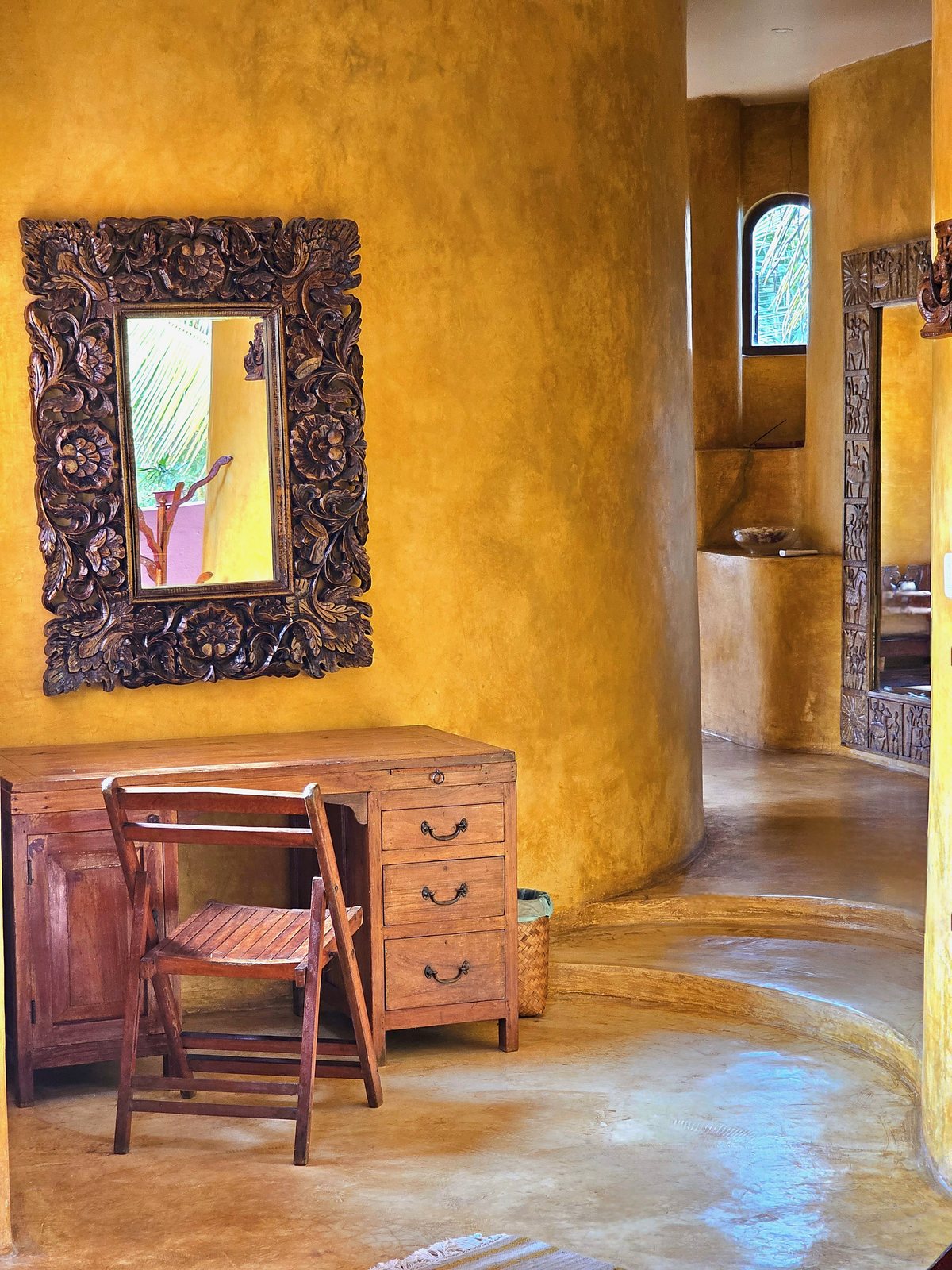 Writing desk and carved mirror in a guest room